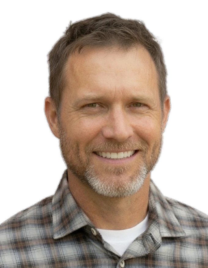 Michael J. Prince: short graying hair, trimmed gray beard, smiling, in a plaid flannel shirt over a white T-shirt.